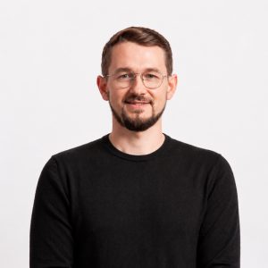 Business professional with glasses and beard smiling, representing financial auditing expertise. Funds.